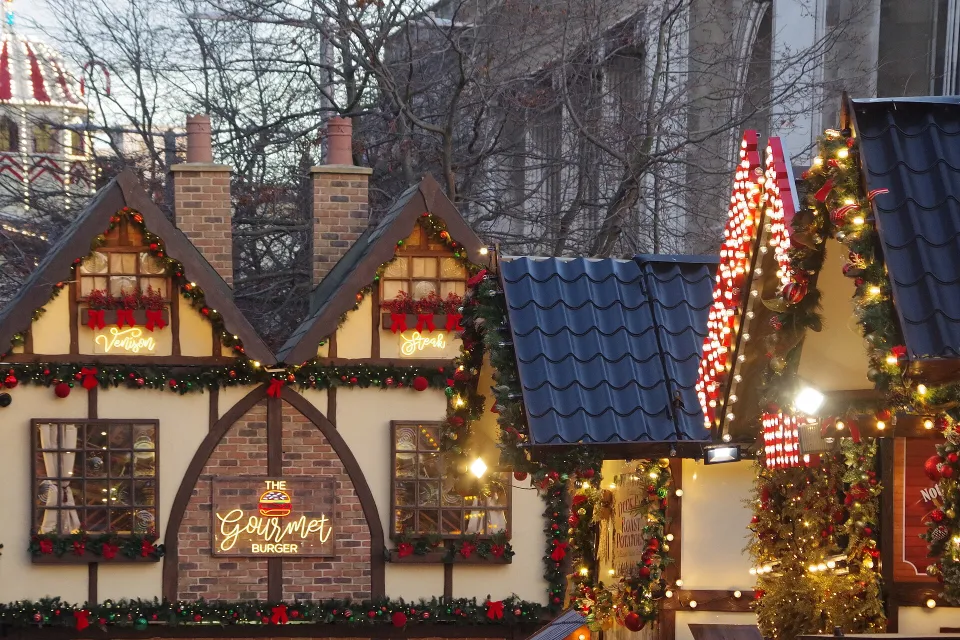 Food cabins built to look like half-timbered cottages, covered in garlands, red bows and warm white lights.